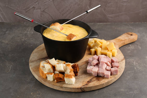 istock Fondue pot with tasty melted cheese, forks and different snacks on grey table 2167182738
