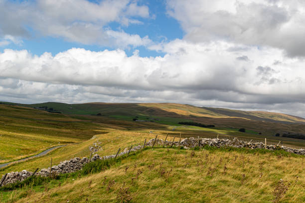 istock Rolling hills with dry stone wall under a cloudy sky in Yorkshire Dales, England. 2167184127