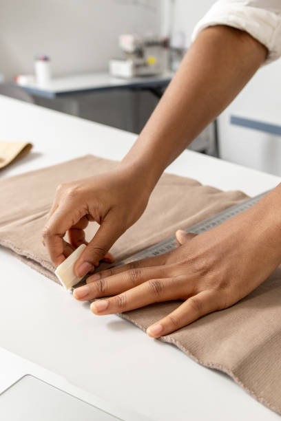 istock Woman tailor working with fabric marked out pattern of the garment making with tailors chalk 2167188622