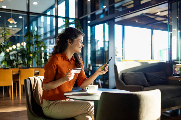 istock Woman using smartphone and credit card in bright cafe 2167188824