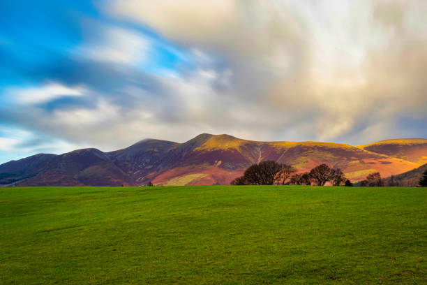 istock Dramatic sky over lush green meadow with rolling hills in the background at sunset in Lake District, England. 2167189372