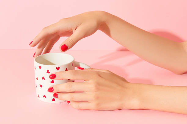 istock Womans hands with red manicure holding cup on pink background. Minimalist nail design 2167200981