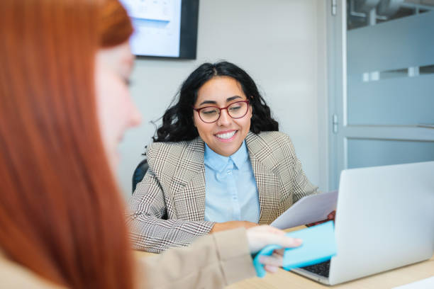 istock Young businesswomen exchanging documents in modern office 2167202424