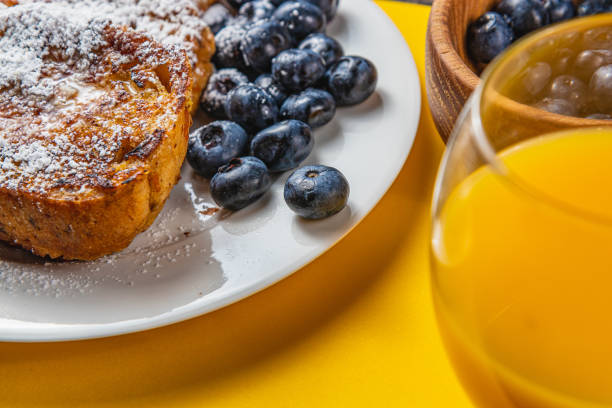 French toast on a white plate with blueberries and orange juice for breakfast