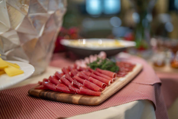 A close-up view displays a selection of cured meats on a wooden board, part of an inviting breakfast buffet set in a boutique hotel's self-service area.