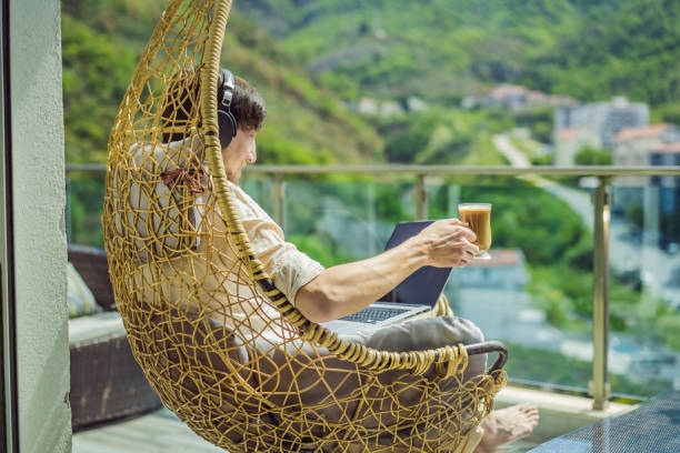 istock Handsome caucasian man sitting on the terrace working from home using computer laptop. Young man teaches a foreign language or learns a foreign language on the Internet on his balcony. Online language school lifestyle 2167215355
