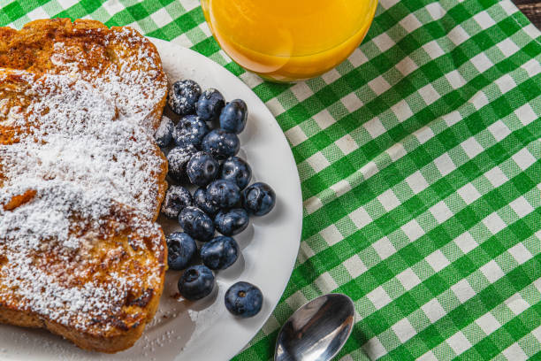 French toast on a white plate with blueberries and orange juice for breakfast