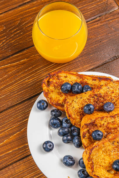 French toast on a white plate with blueberries and orange juice for breakfast