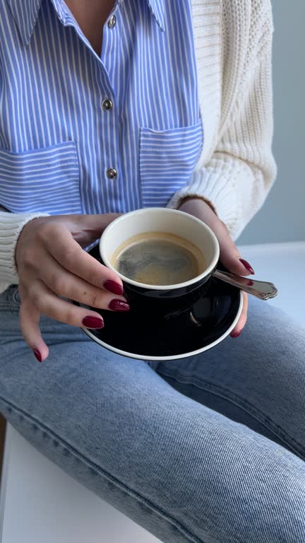 Woman with a cup of black coffee in a casual outfit at home
