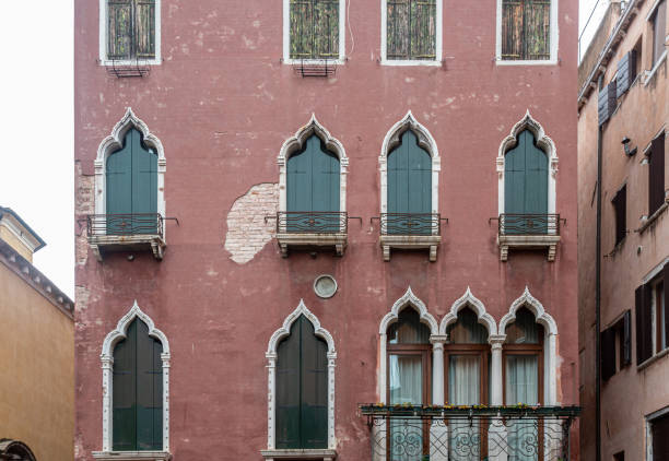 Venice, Italy - June 1st 2024:  Facade of an old palace facing a canal with a doorway for guest arriving in gondolas and a garage for your own boat