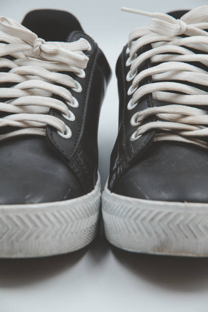 istock shoe sneaker on white background, close up of sneaker on white background, old black generic sneakers on white background. 2167228519