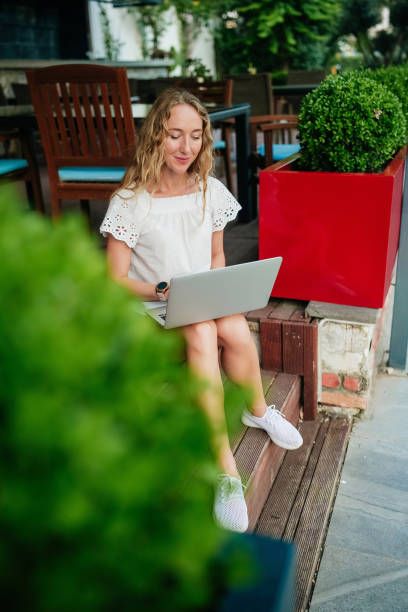 istock Young woman using laptop outdoors at a cozy cafe with greenery in summer 2167228809