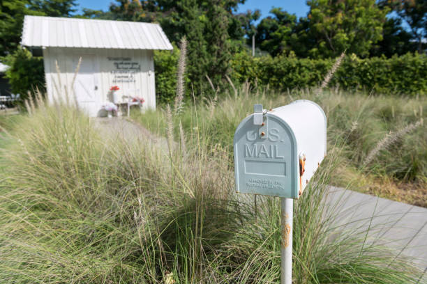 A gray metal U.S. Mailbox isolated on a white background with a wooden post. Shot in studio with a DSLR camera.