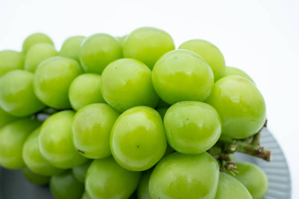 A close-up of a cluster of fresh green grapes, still attached to the vine. The grapes are smooth and tightly packed, showing a plump and juicy texture. This photo vividly captures the freshness and allure of grapes, making it an ideal material for food photography or healthy eating promotions.