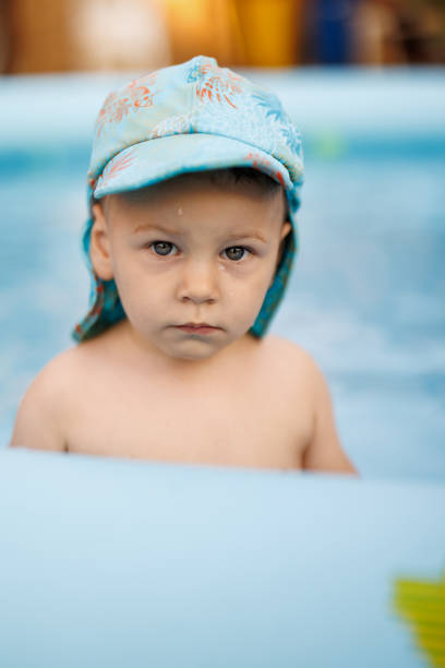 Curious baby boy looking at camera while standing in wading pool