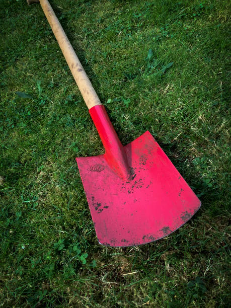 istock Large red handle garden shovel on a green meadow 2167237165
