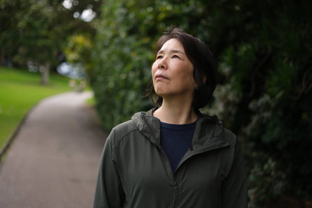 istock Asian woman in a park, looking up 2167246333