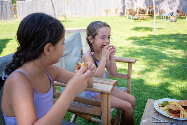istock Little smiling sisters are enjoying the summer days in the shade while having a snack 2167247601