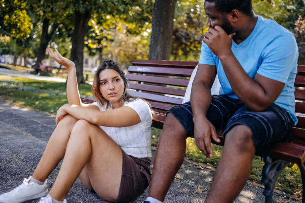 istock Young multiracial couple breaking up at the public park having relationship difficulties while feeling sadness and sitting on ground 2167248954
