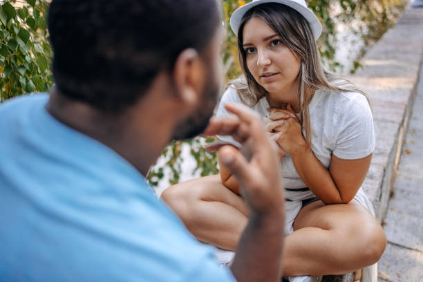 Couple having relationship problems and trying to talk them up while sitting in public park