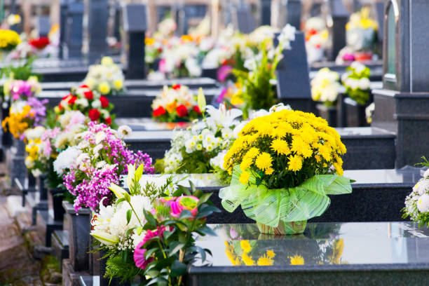 Shallow focus of fabric artificial flowers seen in a marge vase located on a large grave in a rural cemetery. The grave is located in a quite corner of the cemetery, near the church.