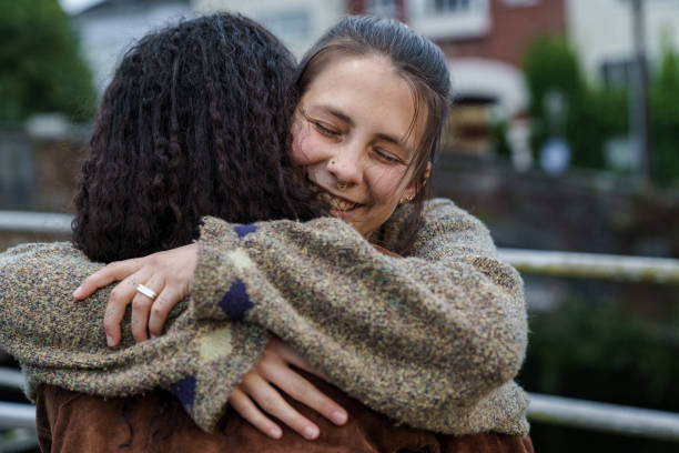 Two interracial women hugging happily.
