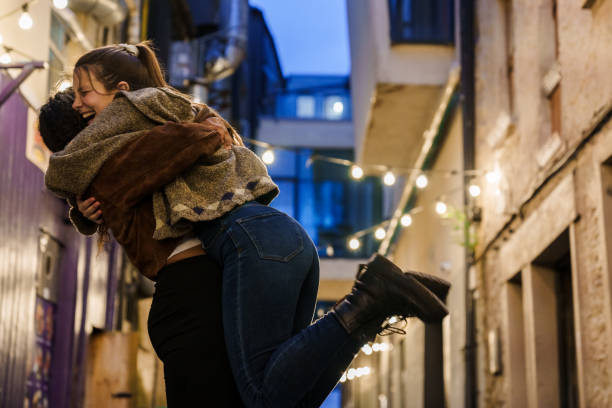 Young couple hugging and kissing in Christmas decorated city at night