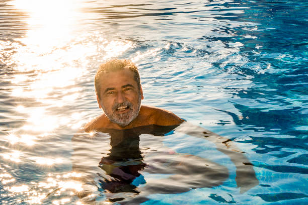 istock Happy mature man bathing in the pool at sunset 2167252413