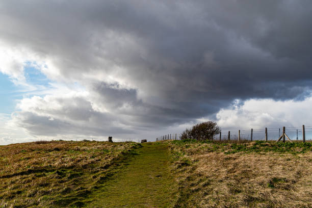 istock Dramatic cloudscape over a rural landscape with a fence line and grassy path leading into the distance. 2167252687