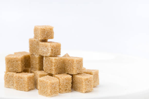 Brown sugar cubes on white plate  on white background. Selective focus.