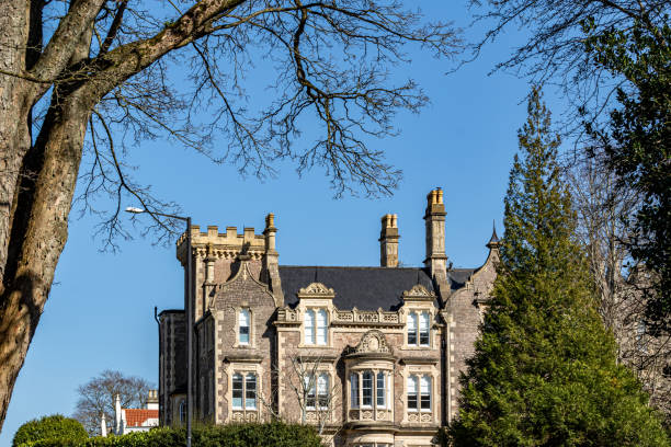 istock Historic stone building with turrets framed by trees against a clear blue sky in Bristol. 2167253900
