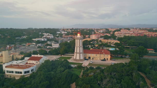 istock High lighthouse blinking cloudy evening sky drone shot. Modern beacon in town 2167254149