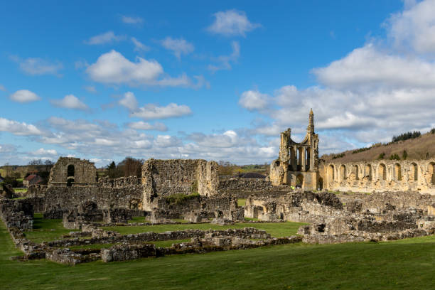 istock Scenic view of ancient abbey ruins under a blue sky with clouds, surrounded by green fields and hills at Byland Abbey 2167254641