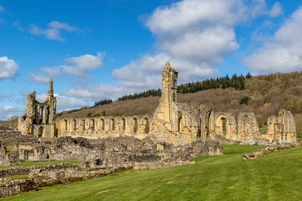 istock Ancient ruins of a medieval abbey with arches and columns, under a blue sky with clouds, surrounded by green grass at Byland Abbey 2167254642