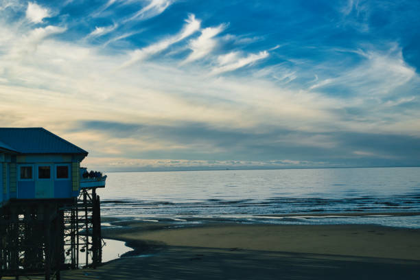 Serene beachscape at dusk with a pier and calm ocean under a vibrant blue sky with wispy clouds in Blackpool, England