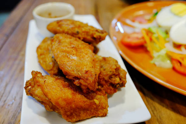 Fried chicken wings and dipping sauce on white plate with vegetable salad with boiled eggs and mayonnaise sauce