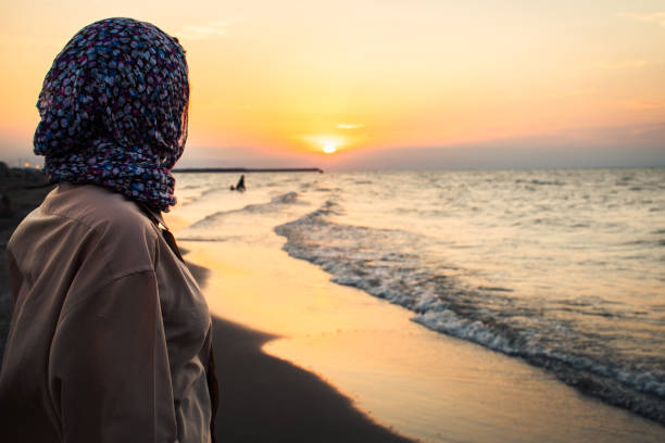 istock Side view Woman standing on beach alone on sunset looking at seascape landscape. Sunset light, golden hour. Nature and journey concept 2167261137