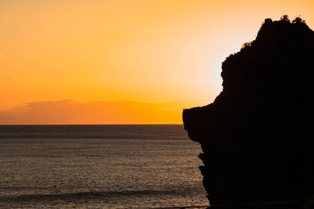 Stunning silhouette of a cliff against a vibrant orange sunset over the Mediterranean Sea in Cinque Terre.