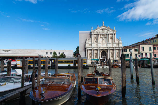 Venice, Italy-April 25, 2024: Water taxis docked in front of Venice's train station with a view of a historic church on a bright day.