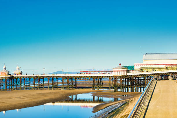 istock Serene seaside pier with clear blue sky reflected in calm water, showcasing tranquil coastal scenery in Blackpool, England 2167268303