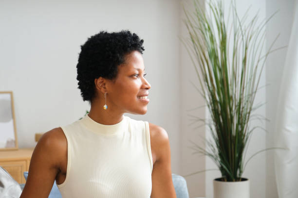 istock Young woman sitting on sofa smiling and looking away 2167269952