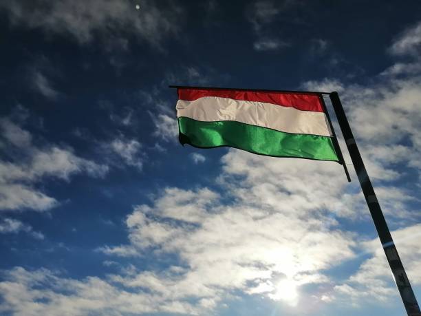 istock Bright Hungarian flag on pole with cloudy and sunny sky 2167271984