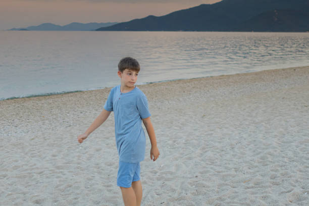 Fun on the ocean beach little blond boy walk on the white sand playing with toy cart