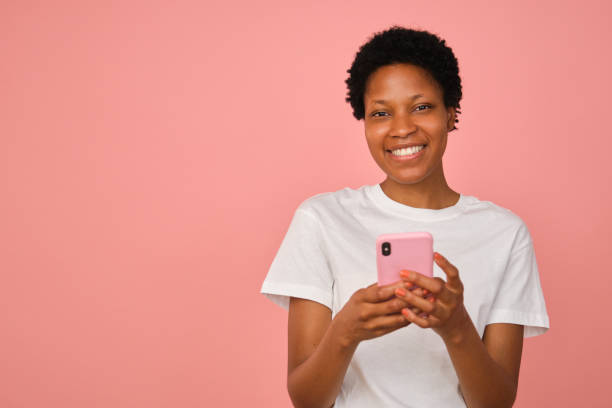 istock Young woman smiling and using smartphone on pink background 2167272421