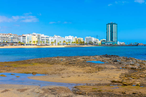 Ocean beach with Arrecife city in the background, Lanzarote, Canary Islands. Picturesque Atlantic coast with a buildings lining the shore