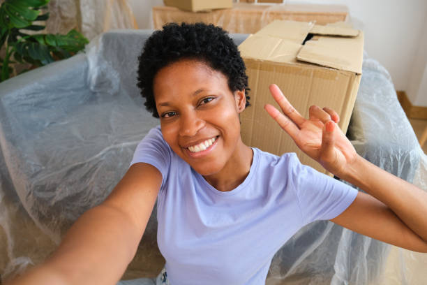 istock Happy woman taking selfie making victory sign while moving home 2167276837
