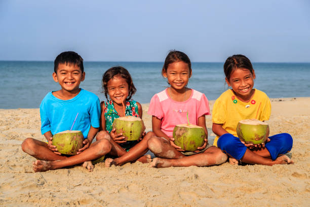 Cambodian children holding coconuts on the beach, Cambodia