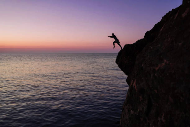 istock Silhouette of a man jumping from high cliffs into the sea 2167279570