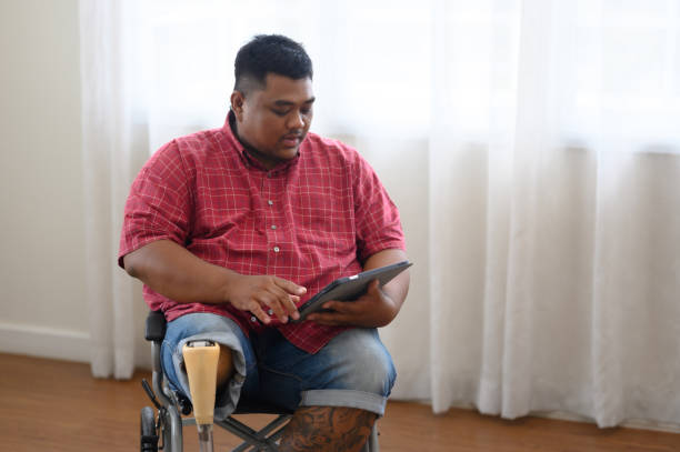 istock A big fat man sits on a wheelchair and uses a tablet. 2167282251