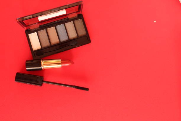 eye shadow mascara lipstick. Makeup tools on a red background with space for text coisspace upper angle.